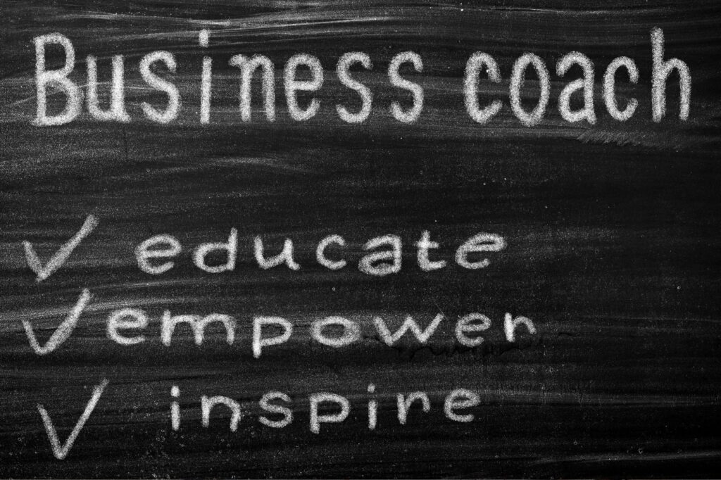 Chalkboard with the phrases 'Business coach', 'educate', 'empower', and 'inspire' written in white chalk.