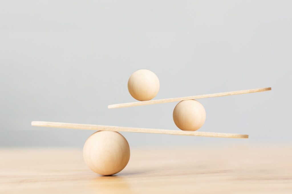 Wooden balance toy with spheres balancing on thin rods in a light, minimalist setup