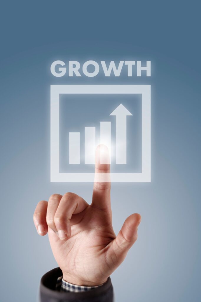 Close-up of a finger pointing at a glowing square with a rising bar chart and an upward arrow, labeled 'GROWTH'.