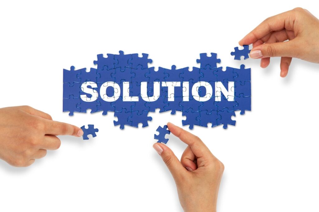 People placing blue puzzle pieces to complete the word SOLUTION, symbolizing collaborative problem solving